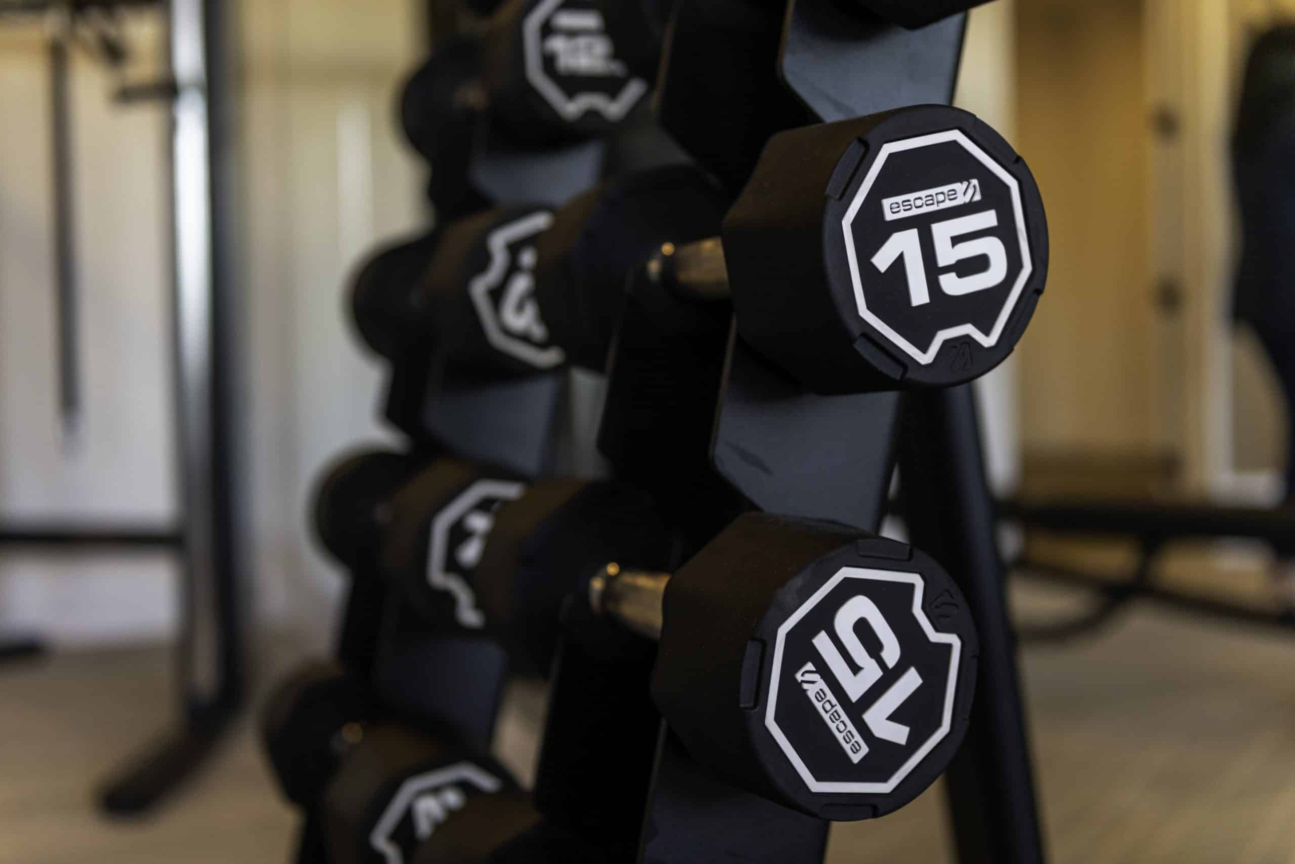 Detail of the fitness center at our apartments in Cypress, featuring free weights on a rack with the number 15 on them.